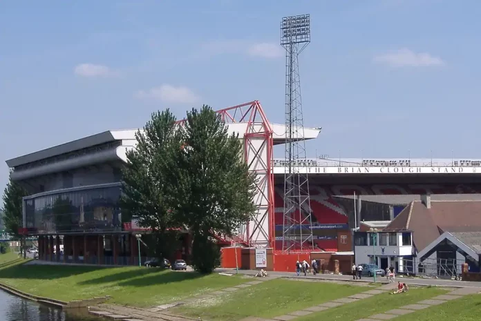 Nottingham Forest's City Ground Stadium by a riverbank, sunny day