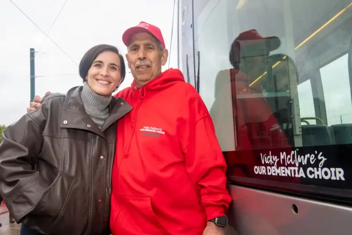 Two people posing near a tram.