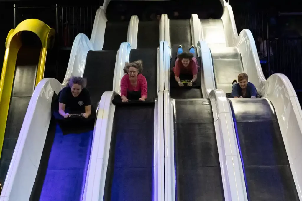 People sliding down indoor slides at Slick City