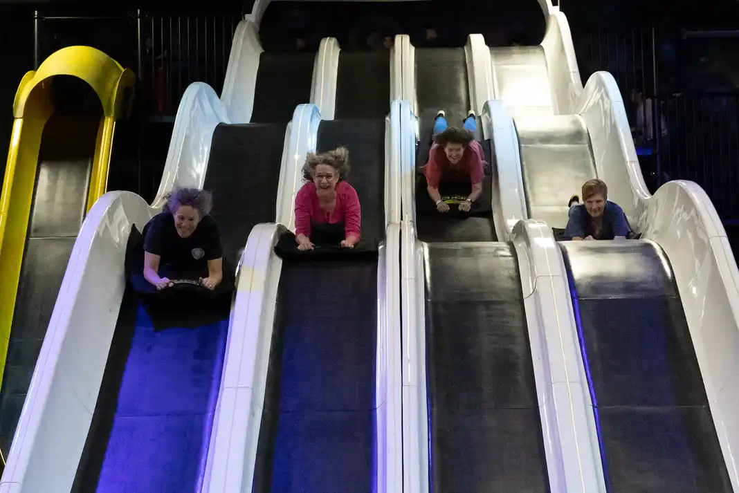 People sliding down indoor slides at Slick City