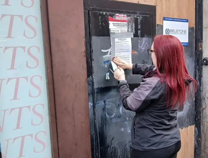 Person posting notice on closed Debenhams shop in Nottingham